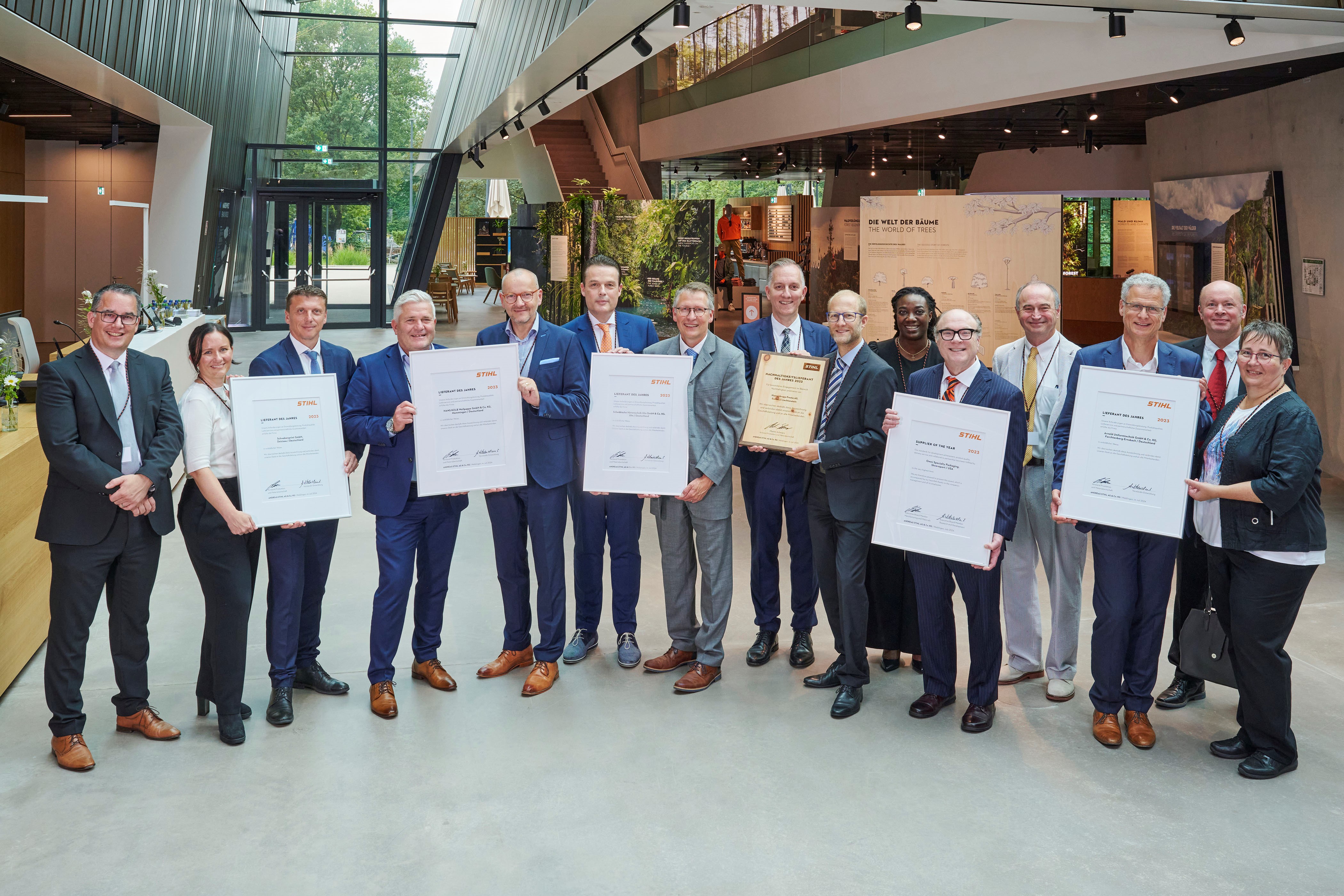 Martin Schwarz, STIHL Executive Board Member for Manufacturing and Materials (left), and Marc Moser, Vice President Purchasing (back right), with the award-winning suppliers in the STIHL Brand World.